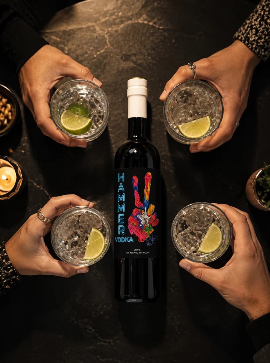 Friends raising cocktail glasses around a Hammer bottle